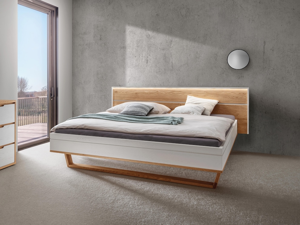 Het hout van het brede hoofdeinde heeft een fijne structuur, hier het bed in wit