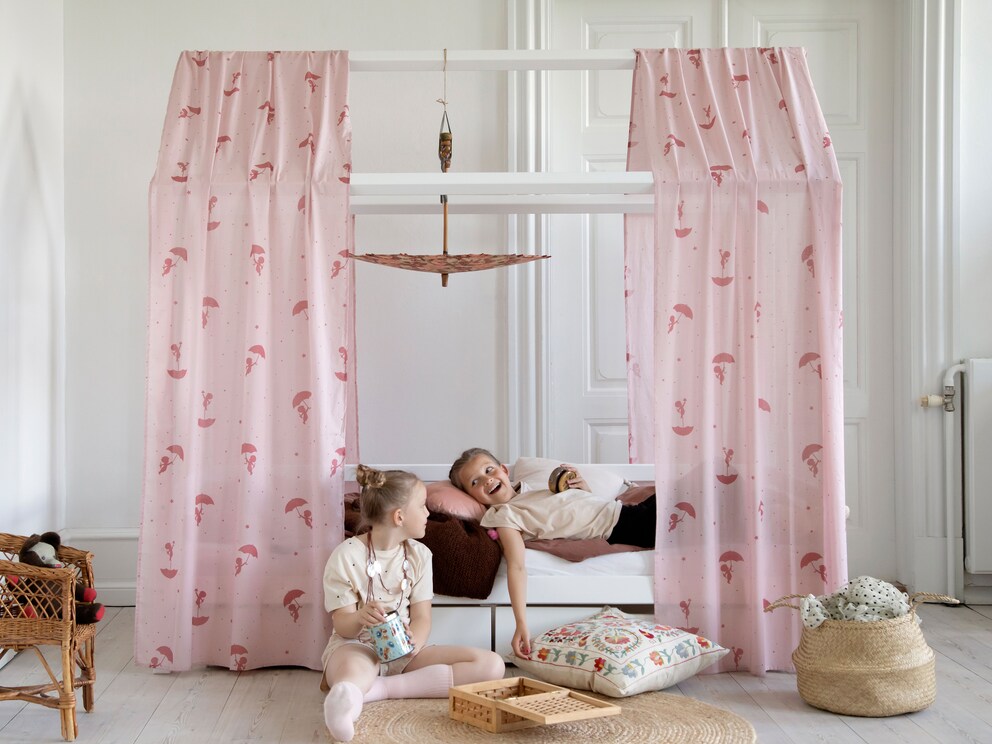 Met gordijnen of stoffen banen wordt het huisbed bijzonder gezellig, hier het bed wit gelakt