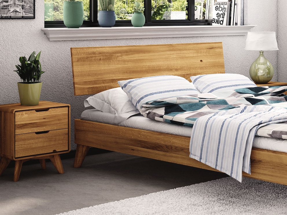Het massief houten bed harmonieert perfect met het wilde eiken nachtkastje
