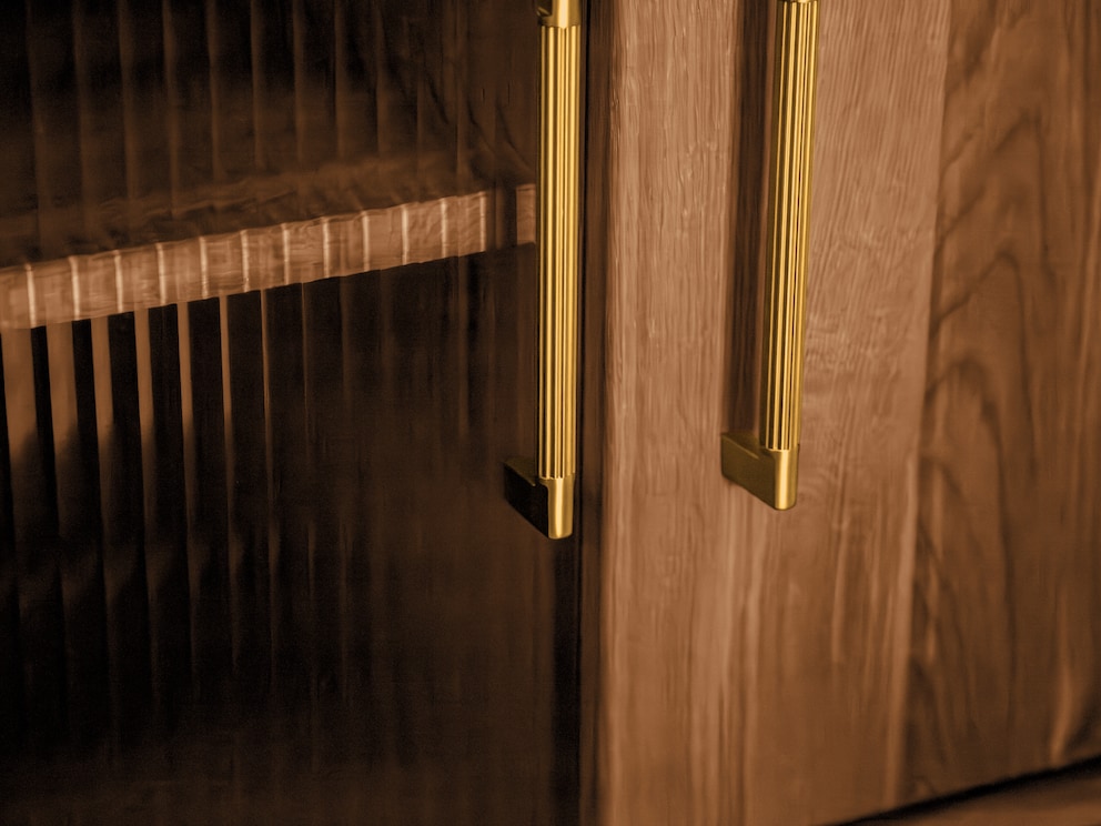 Goudkleurige handgrepen en geribbeld glas benadrukken de mid-century look