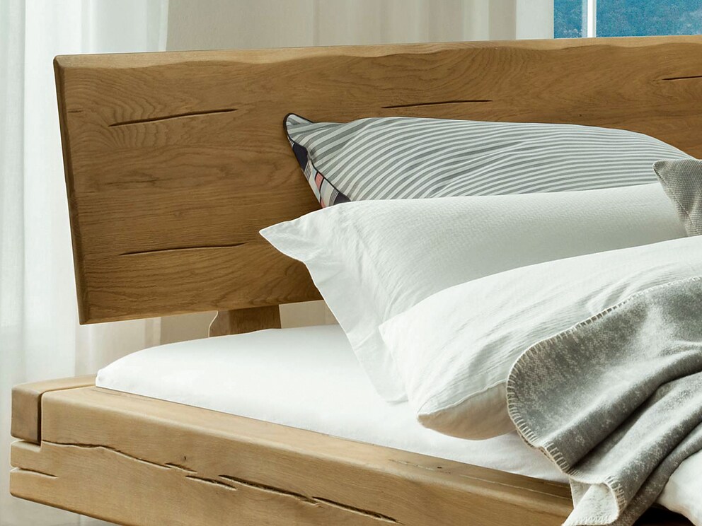 La tête de lit de caractère avec ses bords en bois souligne de manière impressionnante le caractère naturel du lit