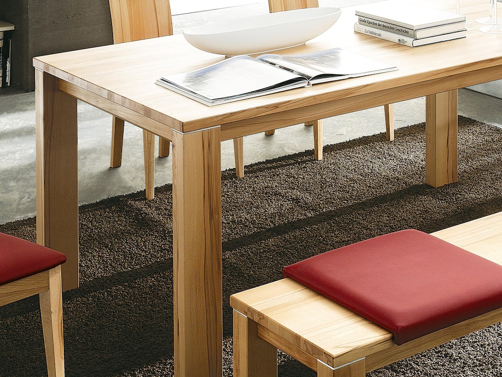 Le cadre en retrait et les pieds rectangulaires confèrent à la table une certaine légèreté - ici en cœur de hêtre