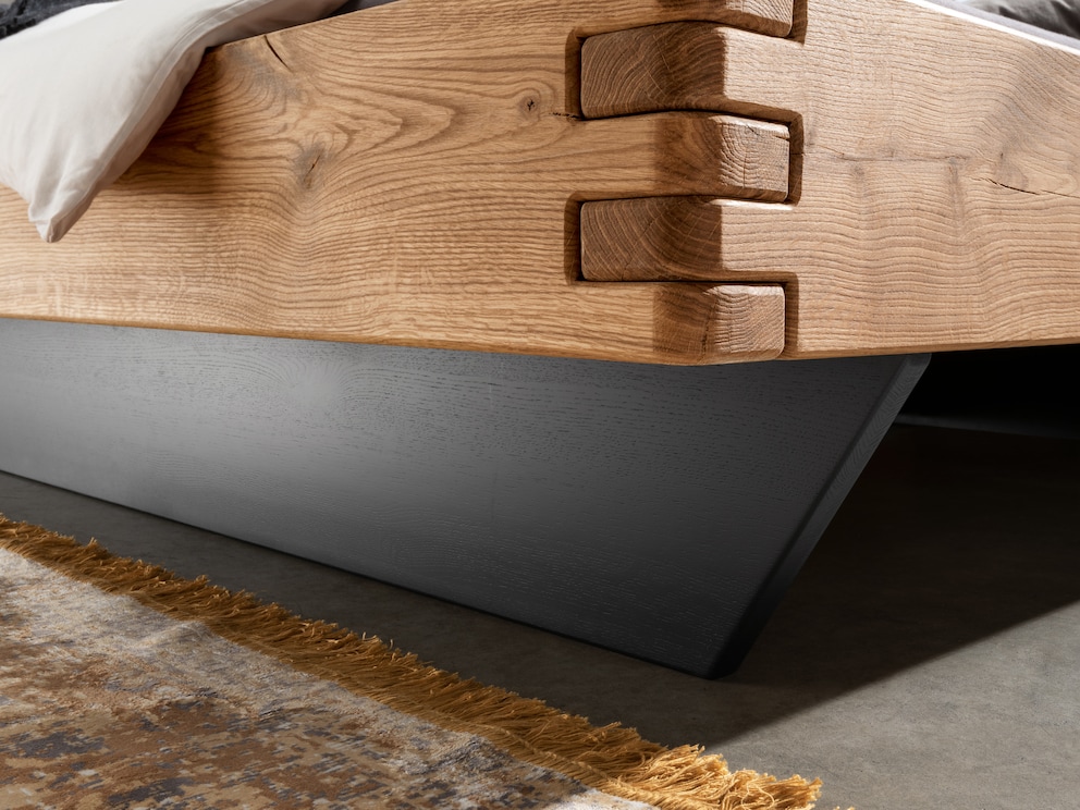 Le soubassement en bois donne au lit une touche de couleur moderne avec le bois teinté noir